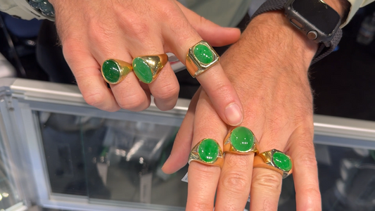 a man showing off six bright green expensive jade rings on his fingers