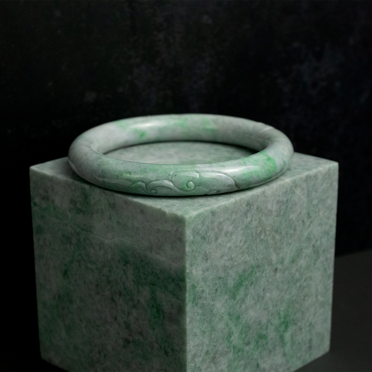 pale green jade bangle carved with a Chinese lingzhi mushroom atop a block of kazakh jade